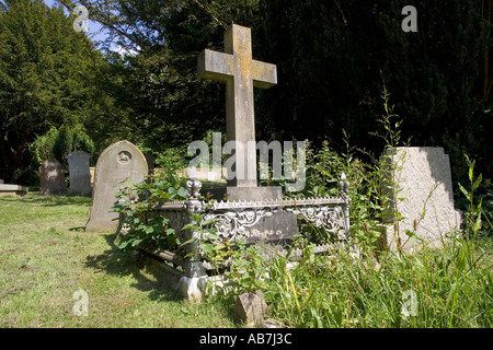 Wildblumen um Kreuz und Grabsteine in Kirchhof Cotswolds UK Stockfoto