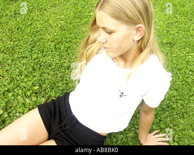 junge Frau sitzt auf Rasen Stockfoto
