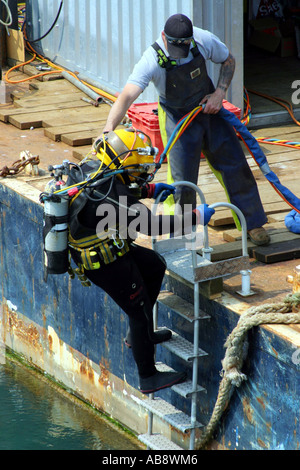 Taucher, die ins Wasser im Hafen von Torquay, zur Durchführung von Wartungsarbeiten am Steg Stockfoto