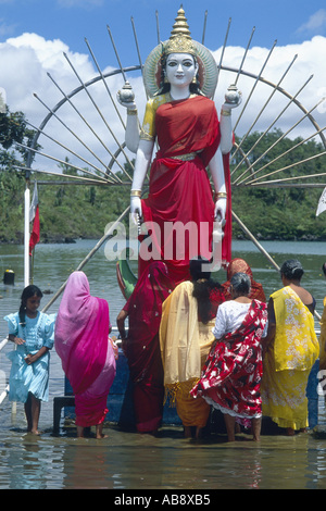 große Statue des Hindi Gott Shiva, stehend im seichten Wasser, umgeben von Frauen und Mädchen, Mauritius. Stockfoto