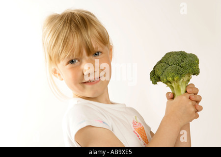 Junges Mädchen mit einem großen Kopf Brokkoli essen Gemüse als Bestandteil einer gesunden, ausgewogenen Ernährung zu fördern Stockfoto