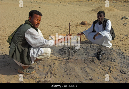 Ababda Stammesangehörige sichern unter Kohlen Brot vom Lagerfeuer in der Wüste Tal Wadi El Gemal Nationalpark Rotes Meer Ägypten Stockfoto