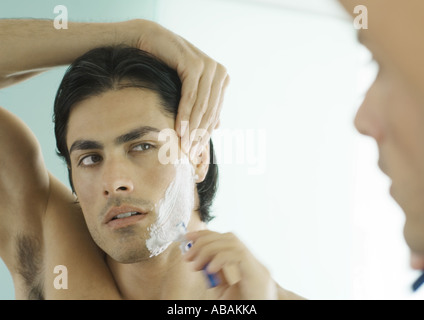 Mann rasieren Wange im Spiegel Stockfoto