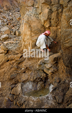 Ababda Stammesangehörige hocken von Wasserloch in Wüste Wadi El Gemal Nationalpark Ägyptens Stockfoto