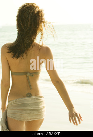 Frau zu Fuß am Strand tragen Sarong über Bikini, Rückansicht Stockfoto