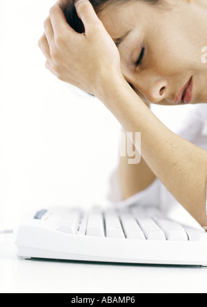 Frau beugte sich über Tastatur Kopf haltend Stockfoto