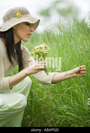 Frau lange Gras hockend mit Blumenstrauß Stockfoto