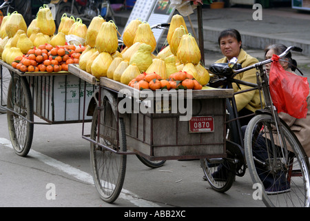 Frauen verkaufen frische Pampelmuse und Orangen aus dem Fahrrad Wagen in der Nähe von dem Markt in Yangshuo, China Guilin Bereich Stockfoto