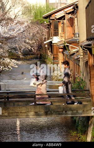 Frauen gekleidet in traditioneller Kleidung Kreuz Shirakawa River, Gion während Cherry Blossom Saison, Kyoto, Japan Stockfoto