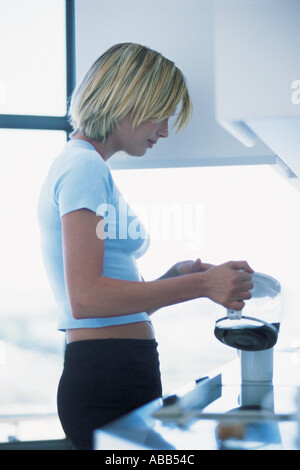 Büroangestellte, die Kaffee in die Tasse Gießen Stockfoto