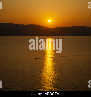 Goldener Sonnenuntergang über die Bucht von Argostoli mit Wellen und Gefolge des Bootes in den Reflexionen auf Kephallonia Insel der griechischen Inseln Stockfoto