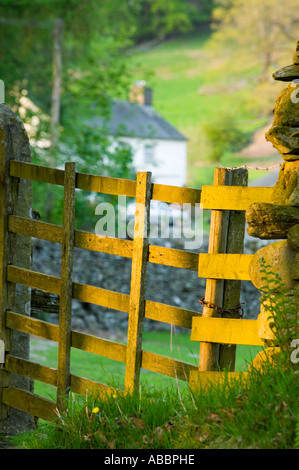 ein traditionelles Lakeland Bauernhaus am Loughrigg Tarn, in der Nähe von Ambleside, Lake District, Großbritannien, gesehen durch ein Hof in der Abenddämmerung Stockfoto