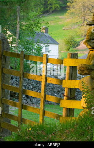 ein traditionelles Lakeland Bauernhaus am Loughrigg Tarn, in der Nähe von Ambleside, Lake District, Großbritannien, gesehen durch ein Hof in der Abenddämmerung Stockfoto