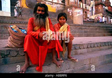 Indische Priester und kleiner Junge sitzt neben dem heiligen Fluss Ganges in Banaras Stockfoto