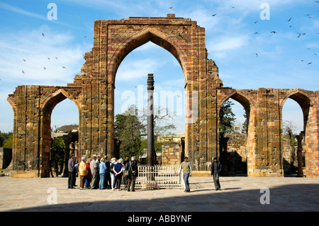 Gruppe von Touristen stehen rund um die eiserne Säule mit zerstörten Bögen einer Moschee Qtab Minar Delhi Indien Stockfoto