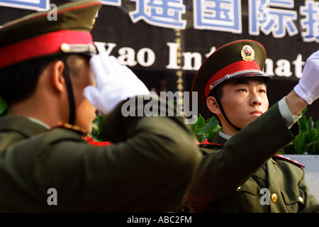 Ein chinesischer Soldat salutiert (links), während sein Kollege (rechts) konzentriert sich auf die Flagge hissen, während eine Fahne, die Erhöhung der Zeremonie. Stockfoto