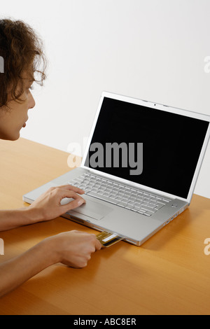 Frauen setzen eine Kreditkarte innerhalb der cd Rom Eröffnung eines Laptop-Computers Stockfoto