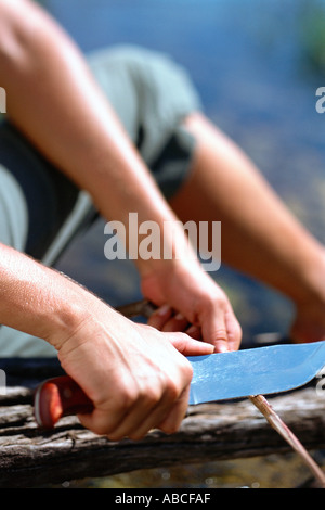 Man schneidet einen Holzstab Stockfoto