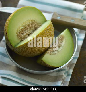 Galia Melone mit Messer auf Metallplatte mit gestreiften Leinentuch Stockfoto