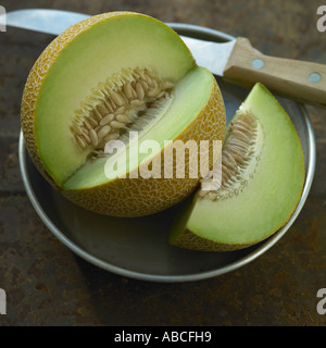 Galia Melone mit Messer auf Metallplatte Stockfoto