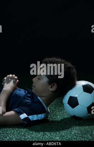 Jungen mit Fußball als Kissen schlafen Stockfoto