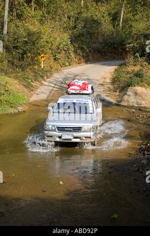 Mit dem Geländewagen fahren Fahrzeugantriebe durch Ford auf schmalen Straße in der Nähe von Mae Hong Son Nord Thailand Stockfoto