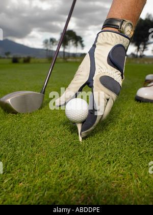 Mann, die Platzierung Golfball auf tee Stockfoto