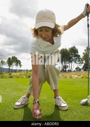 Frau platzieren Golfball auf tee Stockfoto