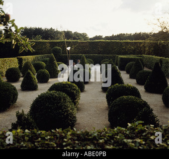 Ein Raster aus großen Kasten Kugeln und Zapfen in Kies, umgeben von einem niedrigen und dann eine höhere Hainbuchen-Hecke Stockfoto