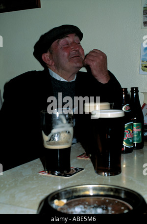 älterer Mann sitzt in einer Bar sein Lieblingsgetränk genießen, Alter Mann mit Mütze sitzt mit dem Kopf in der Luft, lachend, Stockfoto