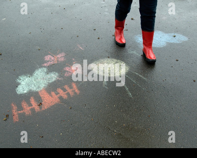 Beine einer Person Frau mit roten Gummistiefel gehen für einen Spaziergang bei Regenwetter auf nasser Fahrbahn mit schwarzen Asphaltdecke Stockfoto