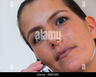 Business-Frau sieht in die Kamera, während sie auf dem Handy ist Stockfoto