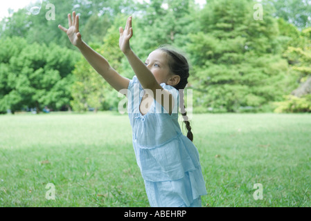 Mädchen stehen auf dem Rasen mit den Armen in der Luft Stockfoto
