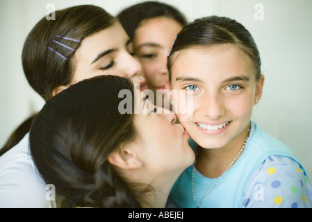 Vier junge Freundinnen, drei eines Mädchens Wange küssen Stockfoto