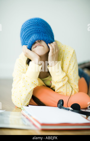 Junge Frau am Boden liegend, herunterziehen stricken Hut über Augen Stockfoto