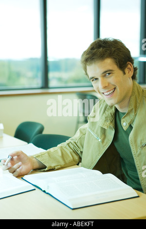 Männliche College-Studenten sitzen in der Bibliothek, lächelnd in die Kamera Stockfoto