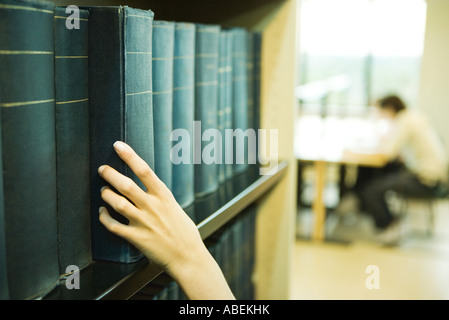 Weibliche Hand nehmend Buch aus Regal in der Bibliothek Stockfoto