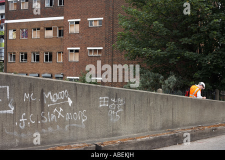 Ein Bauarbeiter macht Notizen vor verurteilt Gehäuse am Standort 2012 Olympische Dorf Stratford London England. Stockfoto