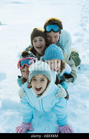 Junge Freunde, gekleidet in Ski-Kleidung, sitzen im Schnee, Porträt Stockfoto