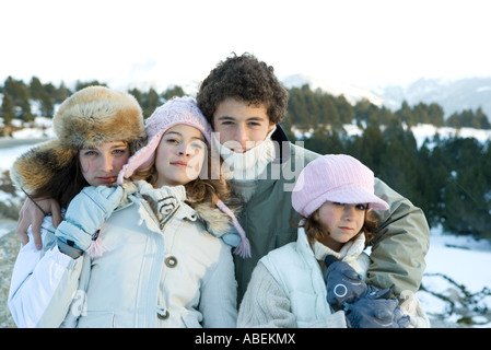 Vier junge Geschwister stehen in verschneiter Landschaft, Porträt Stockfoto