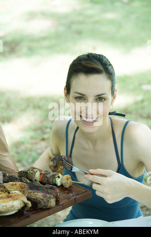 Frau nehmen Stück Grillfleisch aus Fach, lächelnd in die Kamera Stockfoto