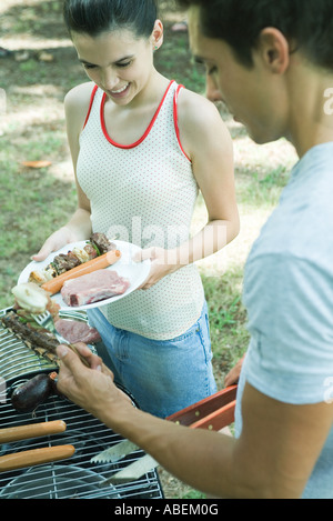 Man serviert Teengirl gegrilltes Fleisch vom Grill Stockfoto