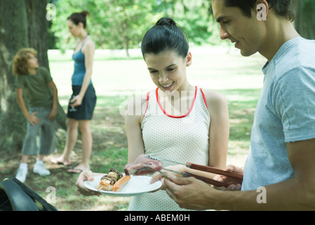 Man serviert Teengirl gegrilltes Fleisch vom Grill Stockfoto