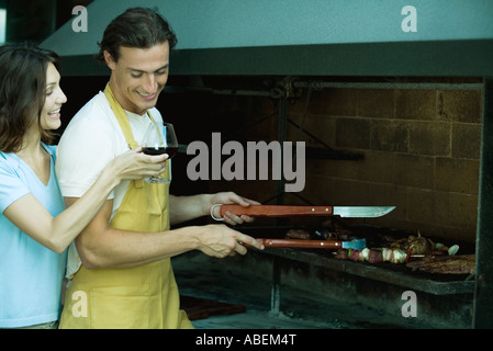 Mann Grill, während Frau Glas Wein für ihn hält Stockfoto
