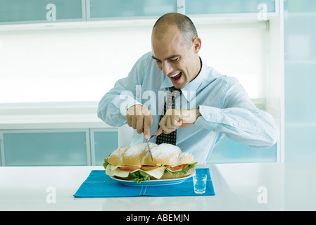 Man schneidet in großen Sandwich mit Messer und Gabel Stockfoto