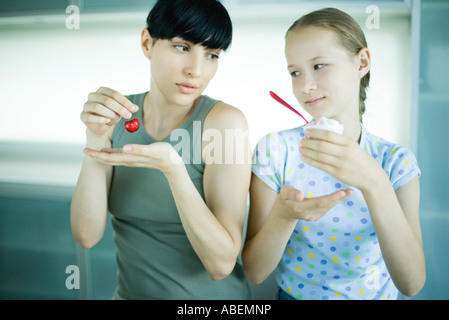 Mädchen halten Eis Dessert, neben Frau mit Kirsche Stockfoto