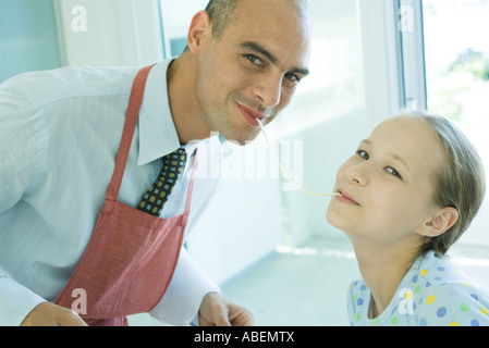 Vater und Tochter teilen Spaghetti Nudel, lächelnd in die Kamera Stockfoto