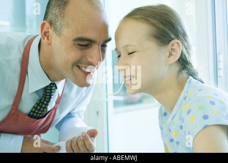 Vater und Tochter teilen Spaghetti Nudel, lachen Stockfoto