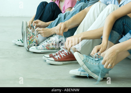 Vier Teenager Freunde binden der Schnürsenkel, alle tragen canvas Schuhe Stockfoto