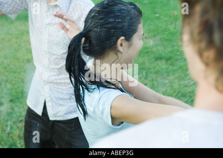 Junge Freunde spielen mit Gartenschlauch, nass Stockfoto